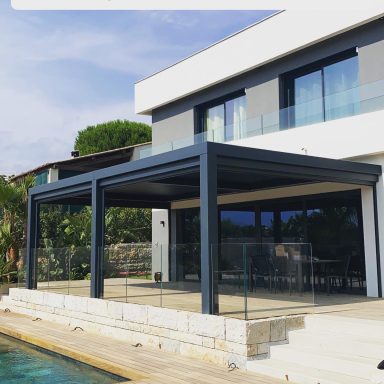 Terrasse moderne avec toit en véranda, bordant une piscine, devant une maison contemporaine.